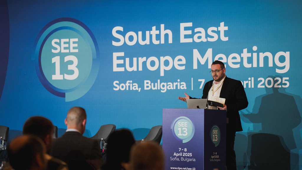 A white man in a black suit, Livio Morina, presents at SEE 13