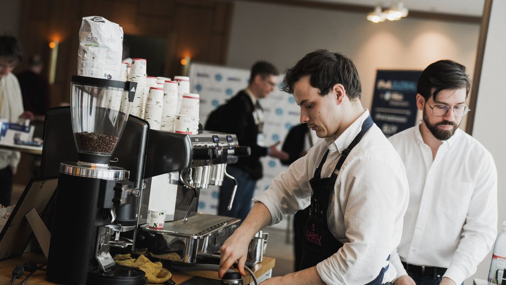 A barista stamps ground coffee into a coffee handle.