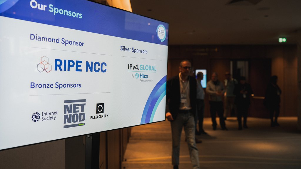 A screen shows the sponsor logos with people walking in the background of the shot.