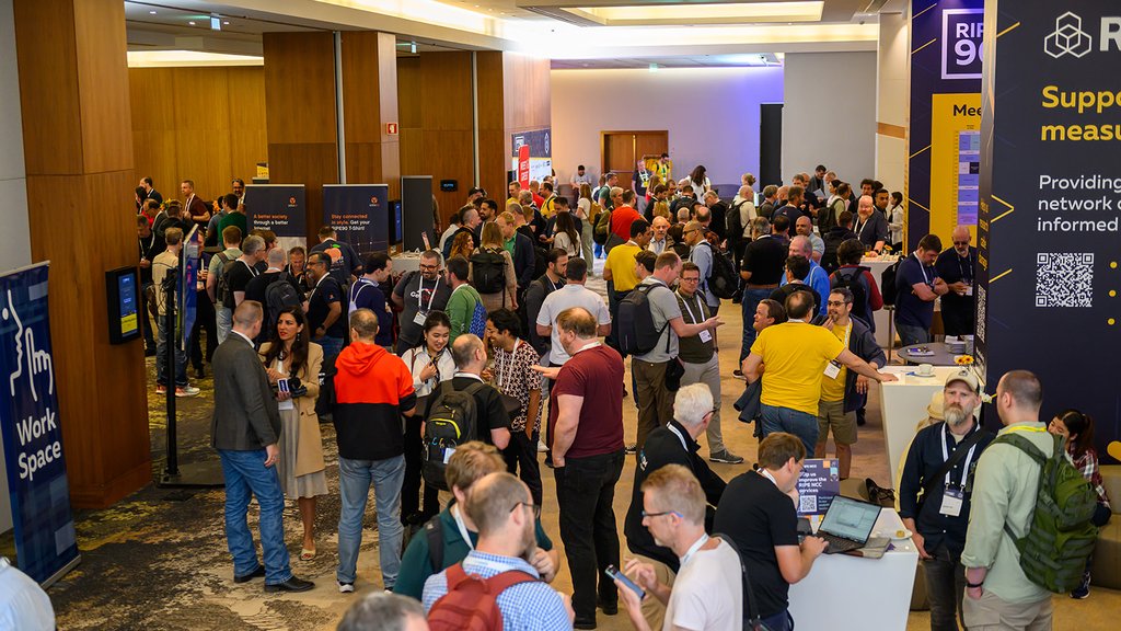A room of people stand and talk during a coffee break.